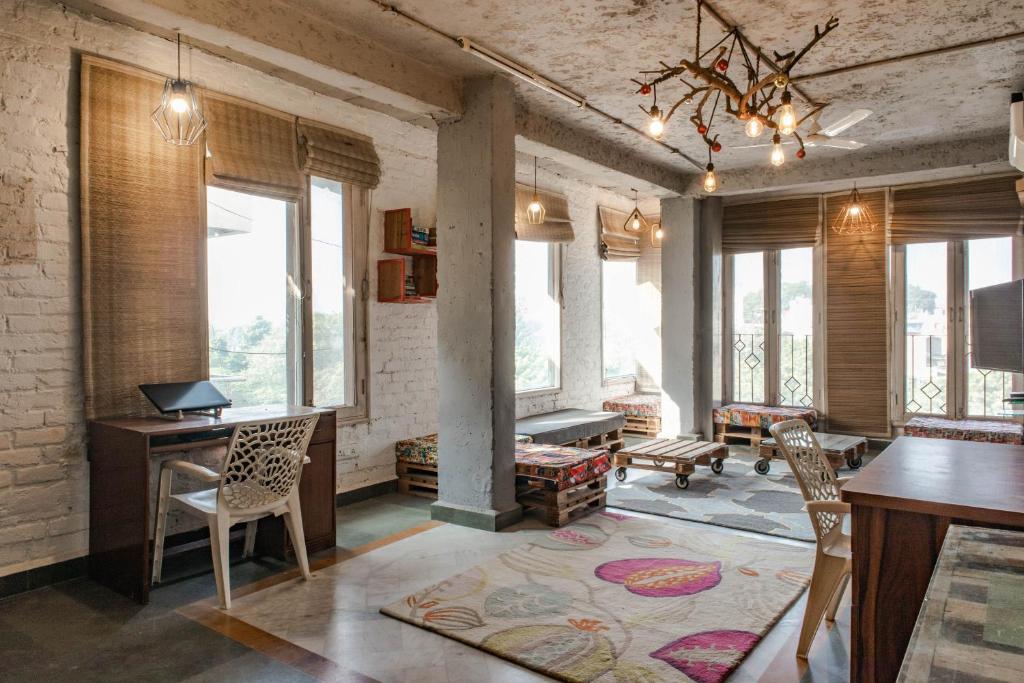 a living room with a table and chairs and windows at JHouse near Bhikaji in New Delhi