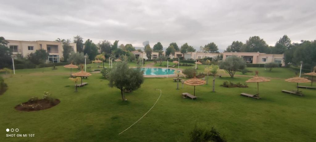 un parc avec une piscine et des parasols sur un champ dans l'établissement Résidence du golf, à Fès