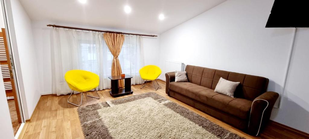 a living room with a brown couch and two yellow chairs at Apartamente elegante in regim hotelier in Iaşi