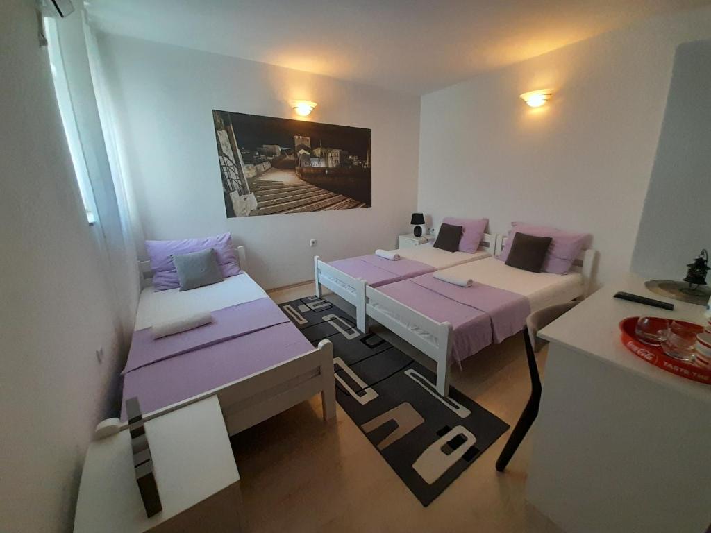 een kamer met 2 bedden en paarse kussens bij Pansion Ponte in Mostar