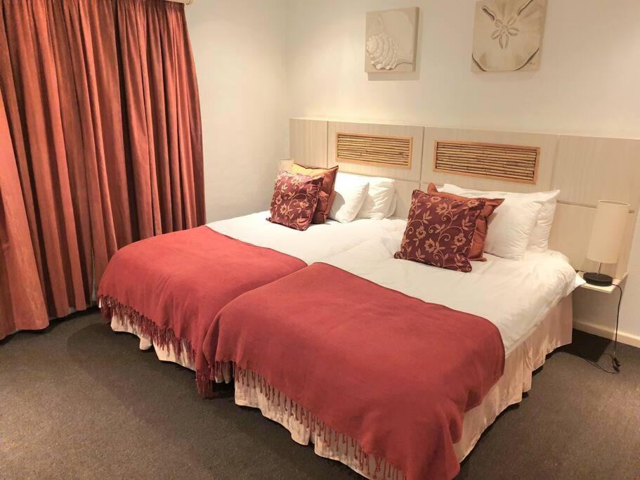 a bedroom with a large bed with a red blanket at Modern 2Bedroom Self Catering unit HBos. in Mossel Bay