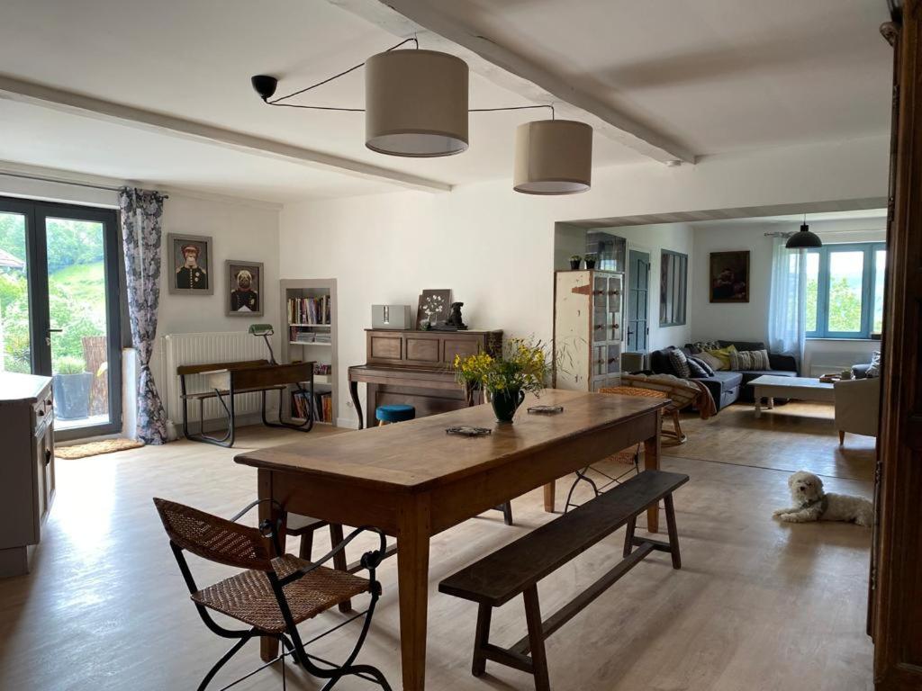 a living room with a large wooden table and chairs at Maison sur cour et véranda in Courzieu