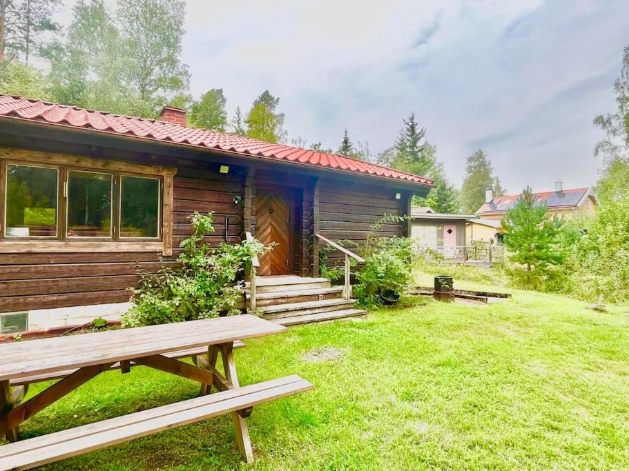 a log cabin with a picnic bench in the yard at Charmig stuga mitt i naturen! in Upplands-Väsby