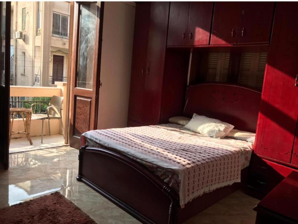 een slaapkamer met een bed met een rood hoofdeinde bij مصر الجديدة - ميدان اسماعيلية - comfortable private room with balcony - Masr el gedida in Caïro