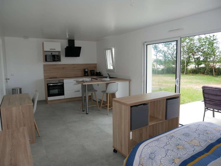 a bedroom with a bed and a kitchen with a table at Studio lumineux avec terrasse in La Roche-sur-Yon