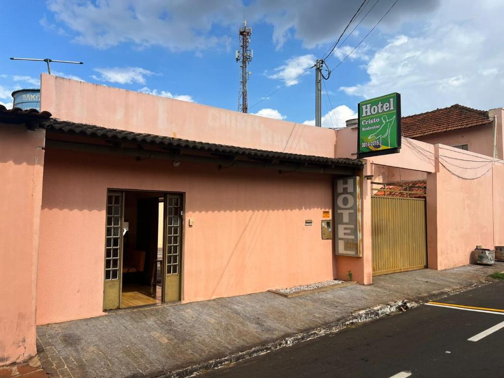 a pink building with a sign in front of it at Hotel Cristo Redentor in Jataí