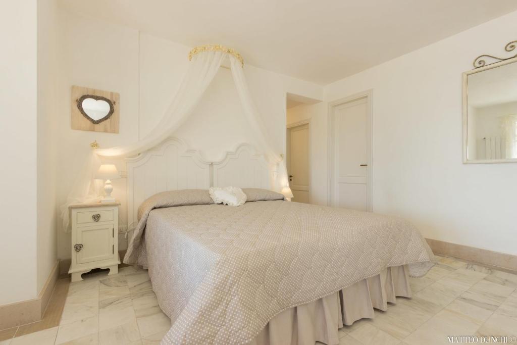 a white bedroom with a bed with a canopy at Hotel - Ristorante Pintadera in Massa