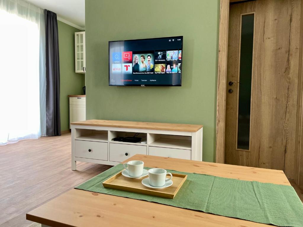 een woonkamer met een tafel en een tv aan de muur bij Apartmány Lavender 