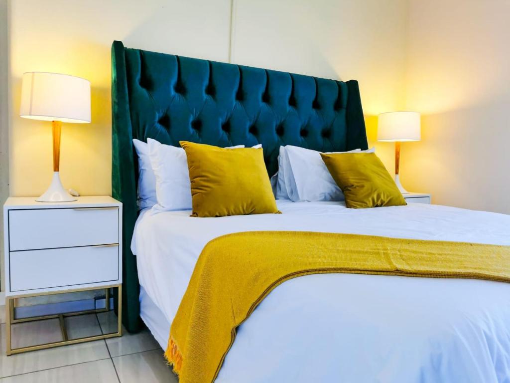 ein Schlafzimmer mit einem großen Bett mit gelben Kissen in der Unterkunft Genesis Guesthouze in Bela-Bela