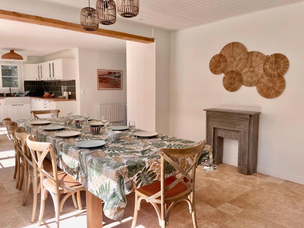 ein Esszimmer mit einem Tisch mit Stühlen und einem Kamin in der Unterkunft Maison en Normandie - 5 min plage Houlgate - Villers sur mer in Auberville