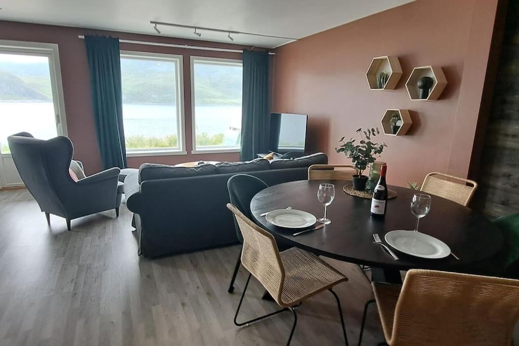 sala de estar con mesa y sofá en Senja, Husøy i Senja. Leilighet med utsikt over fjord og fjell, en Tofta