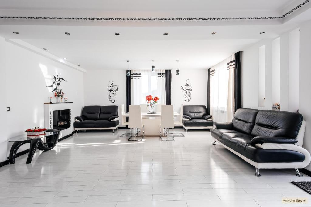 a living room with black leather chairs and a fireplace at Sweet Home Bucovina- Baza perfecta pentru explorarea Bucovinei in Frasin