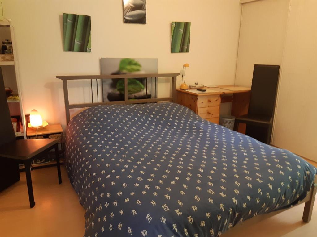 - une chambre dotée d'un lit avec une couverture bleue et blanche dans l'établissement Petit studio - Chambre indépendante au calme, à Landerneau