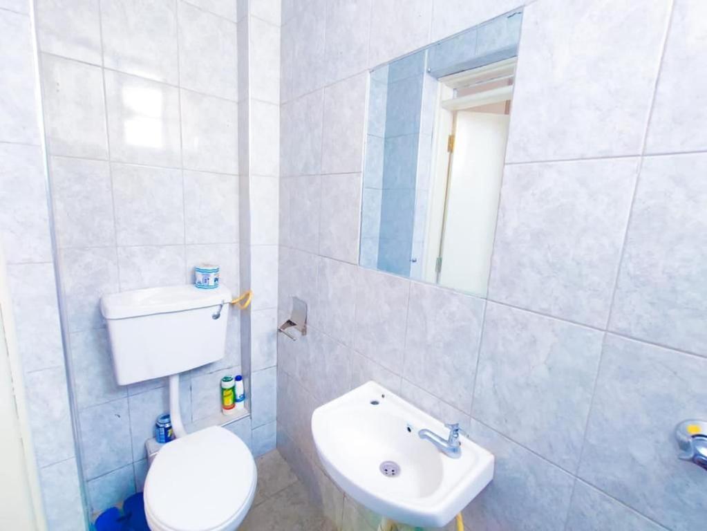 bagno con servizi igienici bianchi e lavandino di Cutie homes_studio a Nairobi