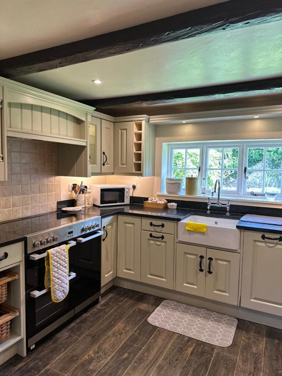 una cocina con armarios blancos y electrodomésticos negros en Gorgeous Cottage in Skirmett with Parking en Henley on Thames