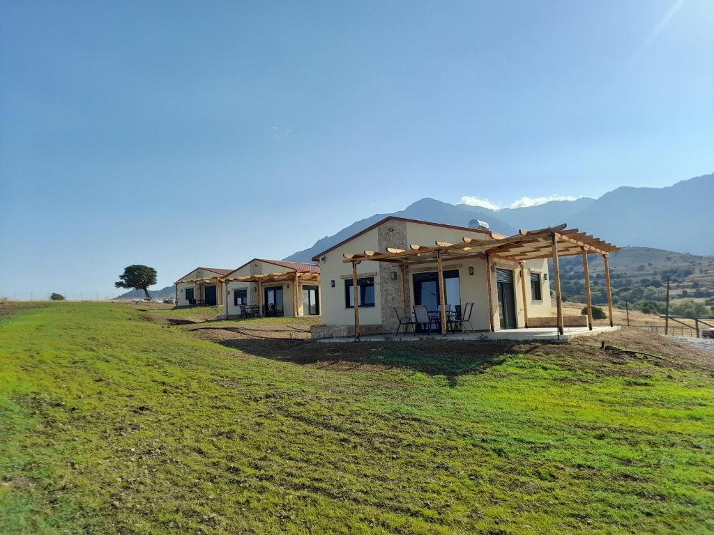 a house on a hill with mountains in the background at Pezoulia Cottages in Samothraki