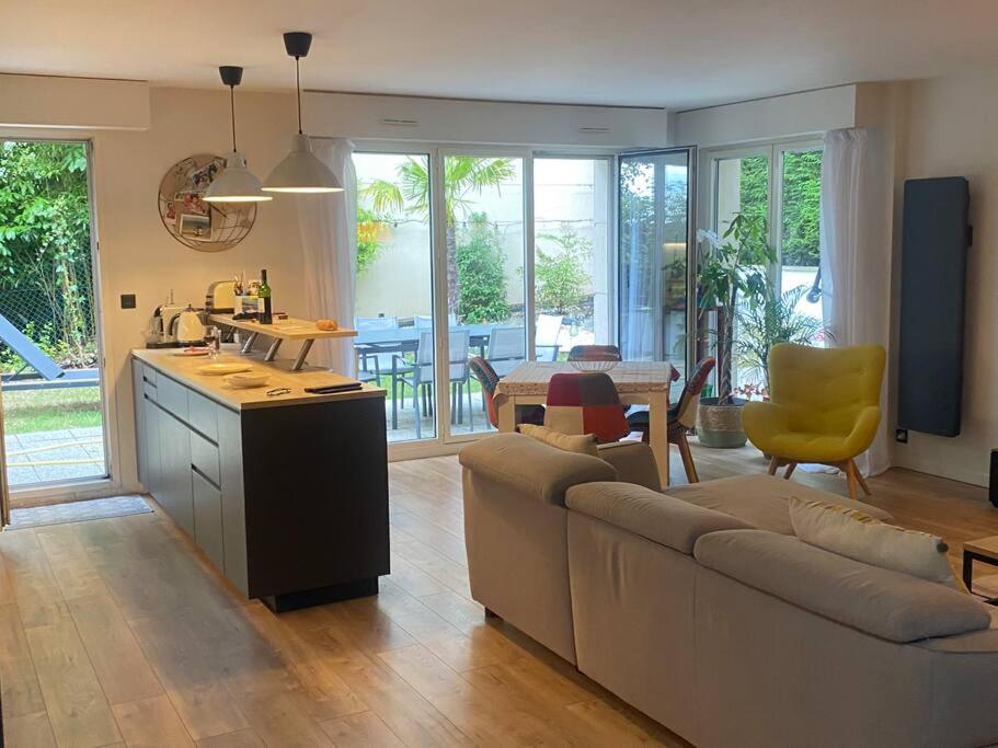 uma cozinha e sala de estar com um sofá e uma mesa em Appartement proche de paris avec jardin em Meudon