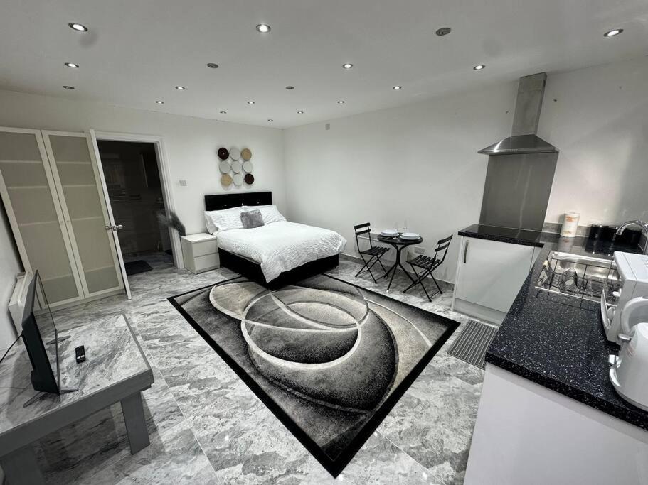 a living room with a bed and a kitchen at Exquisite Luxury Studio in Mitcham