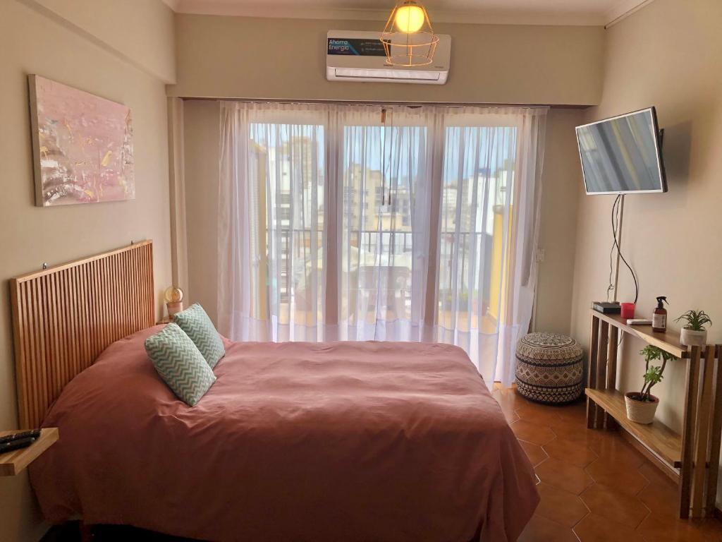 1 dormitorio con cama y ventana grande en El Reino MdQ en Mar del Plata