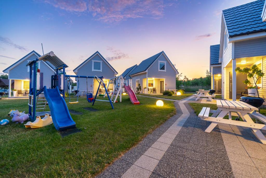 a backyard with a playground with play equipment and houses at Morskie Opowieści in Niechorze