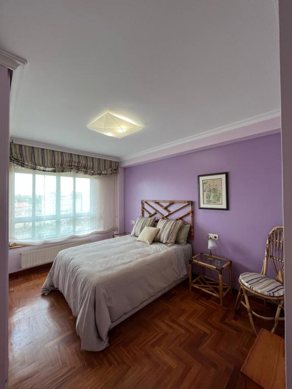 a bedroom with purple walls and a bed and a chair at Apartamento playa Vigo in Vigo