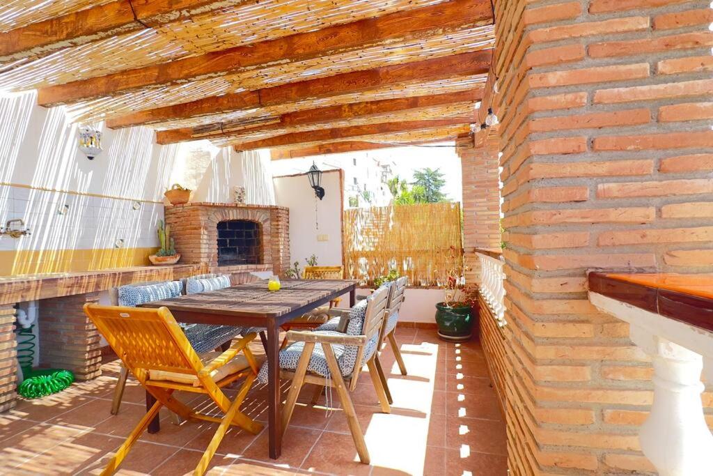 a patio with a wooden table and chairs and a brick wall at Casa Canillas - for solo travelers or small groups of 4 to 6 people in Canillas de Aceituno
