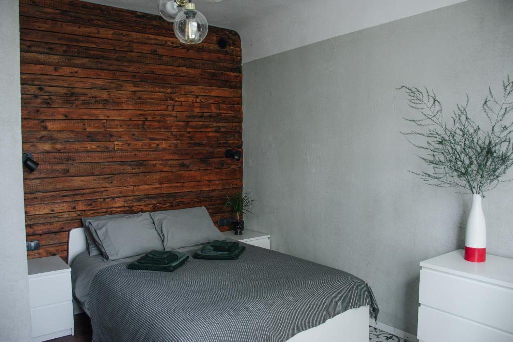 a bedroom with a bed with a wooden wall at "Quiet Center" apartment, close to train station in Tukums