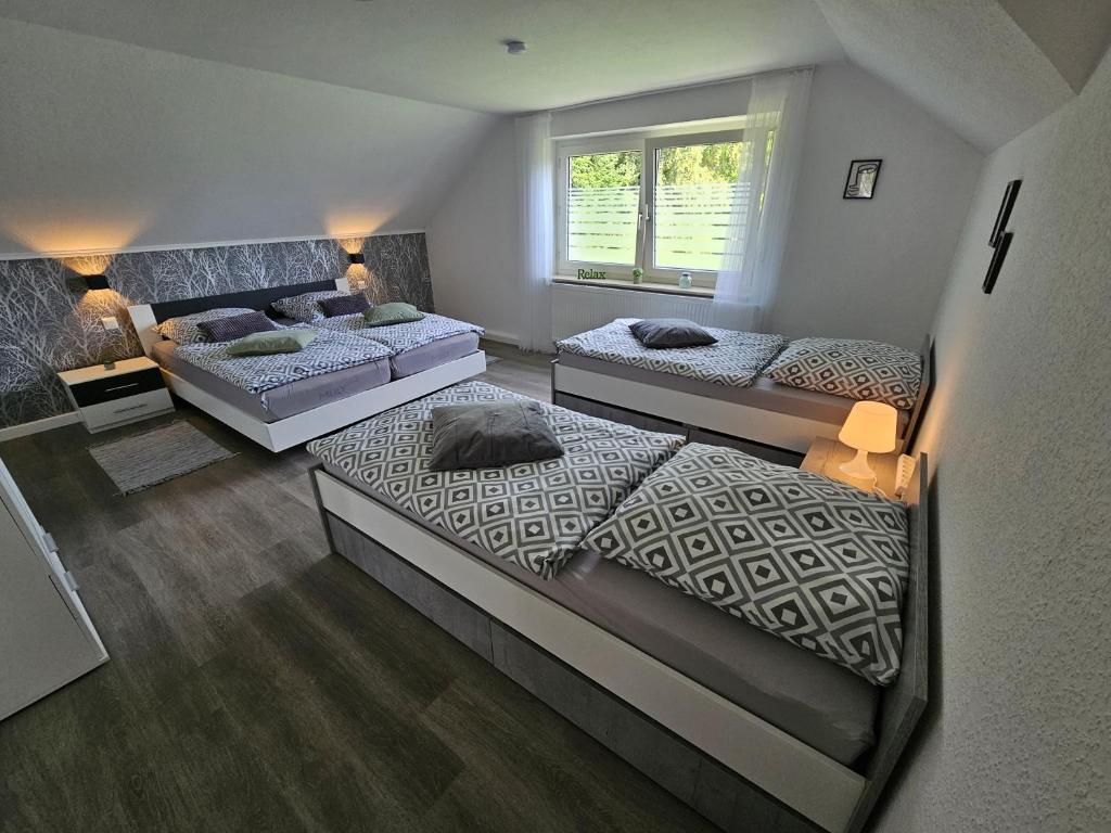 a bedroom with three beds and a window at Ferienwohnung Birkenstraße in Ihlow