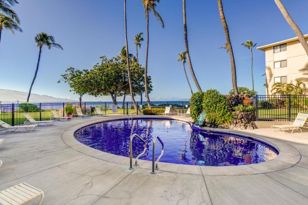 a swimming pool with palm trees and the ocean at Kanai A Nalu 202 in Wailuku