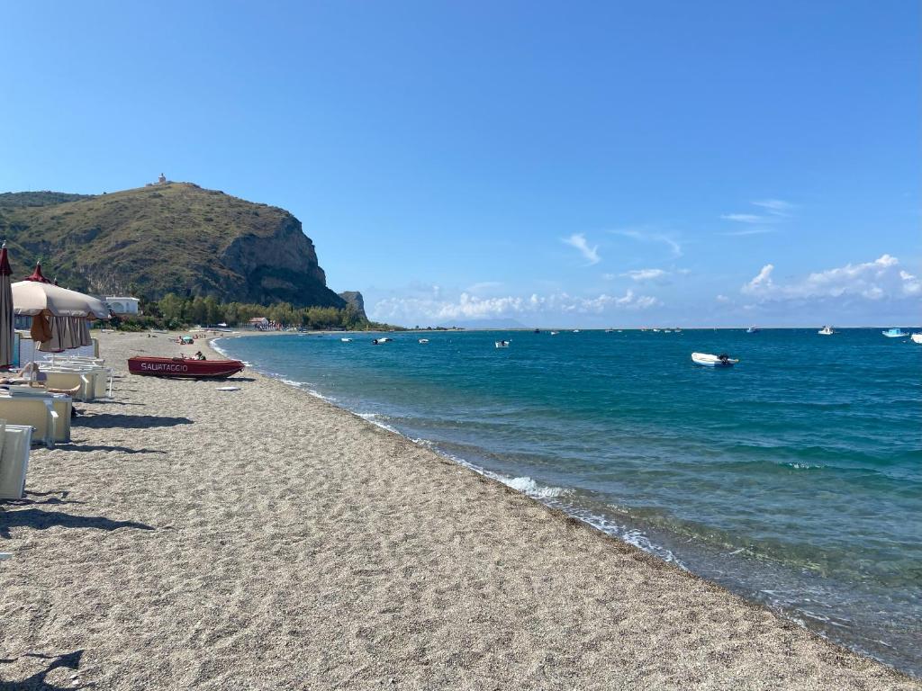 a sandy beach with a boat in the water at Casa Vacanze - Oliveri - Sicilia in Oliveri