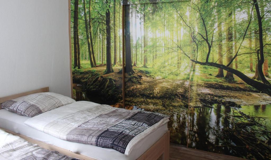 a bedroom with a forest mural on the wall at Ferienwohnung Wippertal Biesenrode in Mansfeld