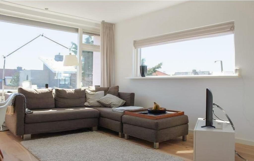 een woonkamer met een bruine bank en een televisie bij Duinzicht 2 in Bergen aan Zee