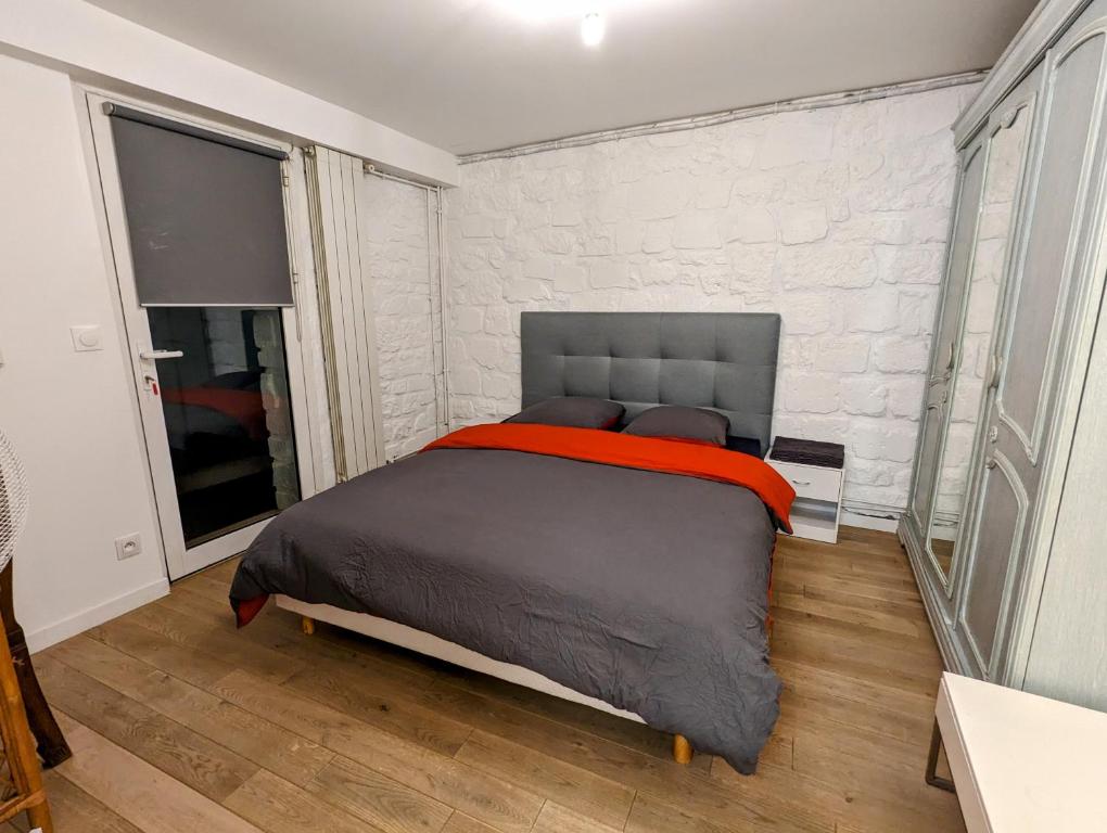 ein Schlafzimmer mit einem Bett mit einer Ziegelwand in der Unterkunft Rez de jardin de maison avec grand jardin exclusif in Villejuif