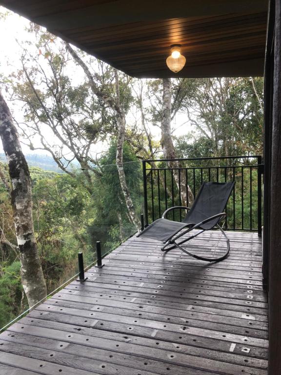 a chair sitting on a wooden deck with a view at Casa Container 80 in Campos do Jordão