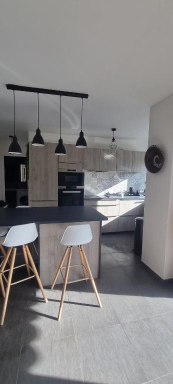 een keuken met twee witte stoelen en een tafel bij TITI'S HOME in Cagnes-sur-Mer