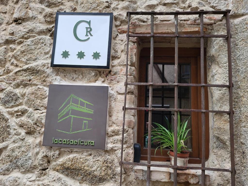 un cartel en un edificio de piedra con ventana en La Casa El Cura, en Madrigal de la Vera