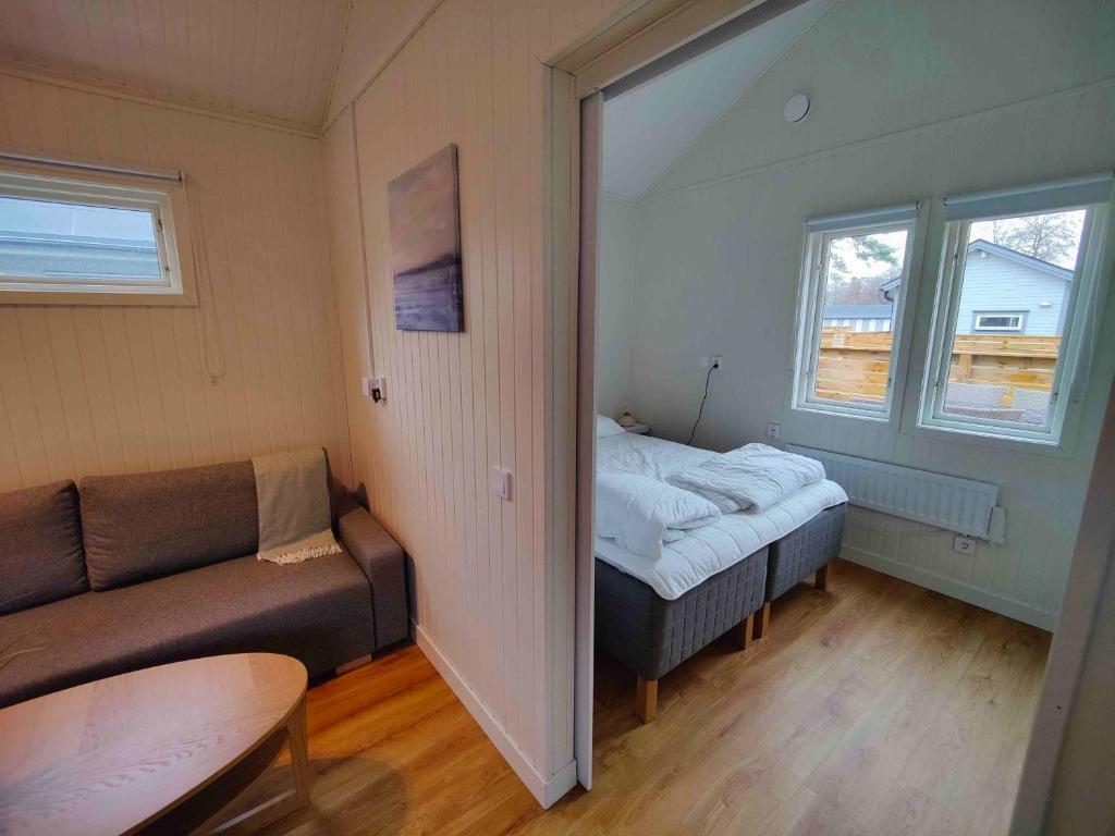 um pequeno quarto com uma cama e um sofá em Strandbyn - Destination Råbocka em Ängelholm