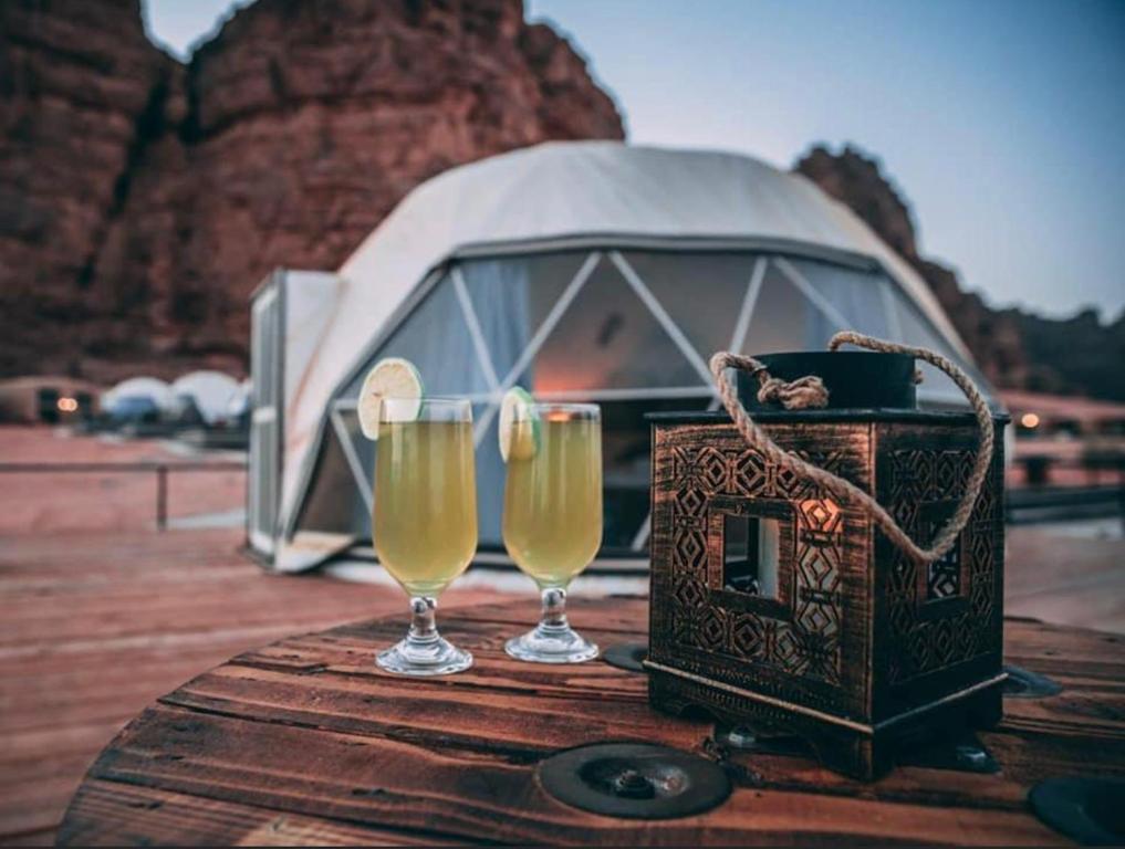 Dwa kieliszki szampana i kamerę na stole. w obiekcie SUN LUXURY CAMP &Tour w mieście Wadi Rum