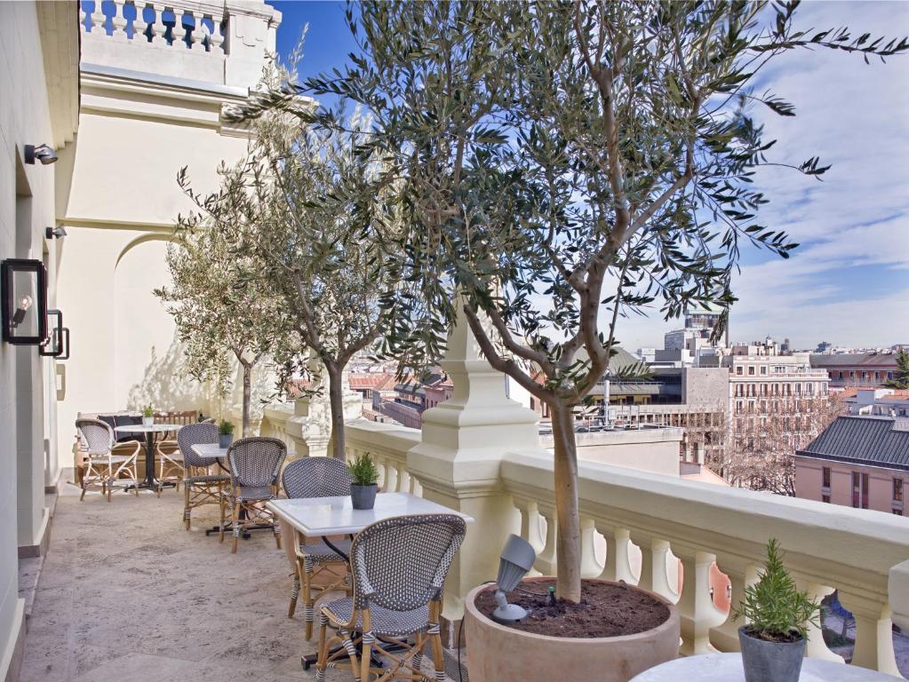 a patio with tables and chairs and a tree on a balcony at The Principal Madrid, Small Luxury Hotels in Madrid