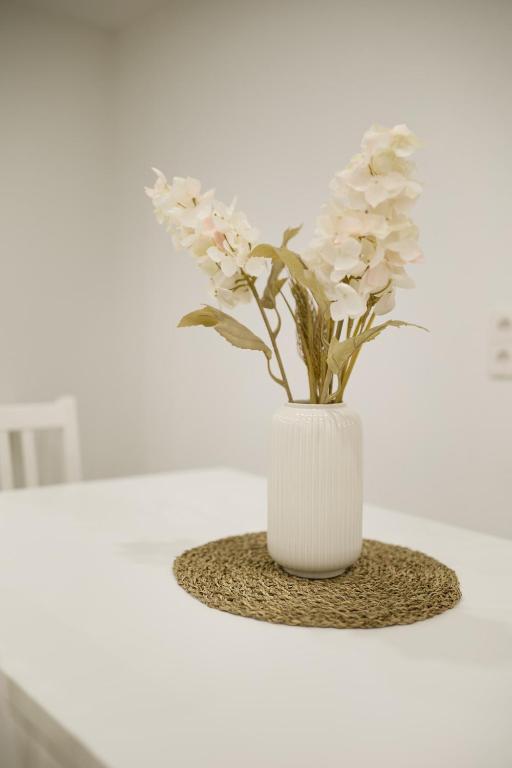 a white vase with white flowers on a table at Ferienwohnung Endingen am Kaiserstuhl in Endingen