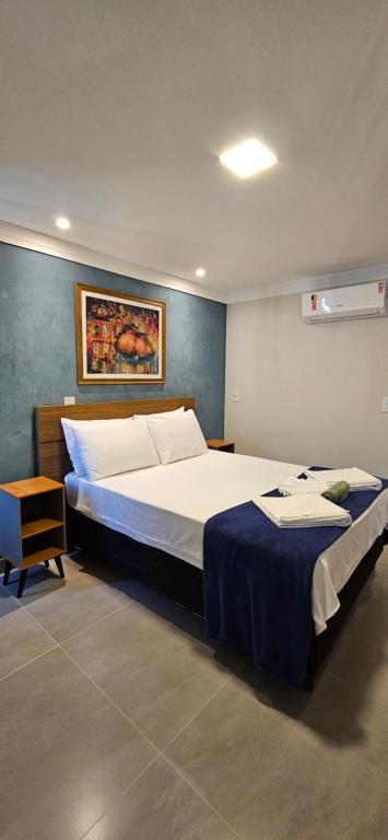 ドミンゴス・マルチンスにあるKitnet Aconchego dos Nobresのベッドルーム1室(ベッド2台付)が備わります。壁には絵画が飾られています。