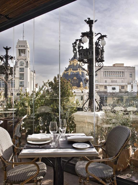 a table and chairs on a balcony with a view of a city at The Principal Madrid, Small Luxury Hotels in Madrid
