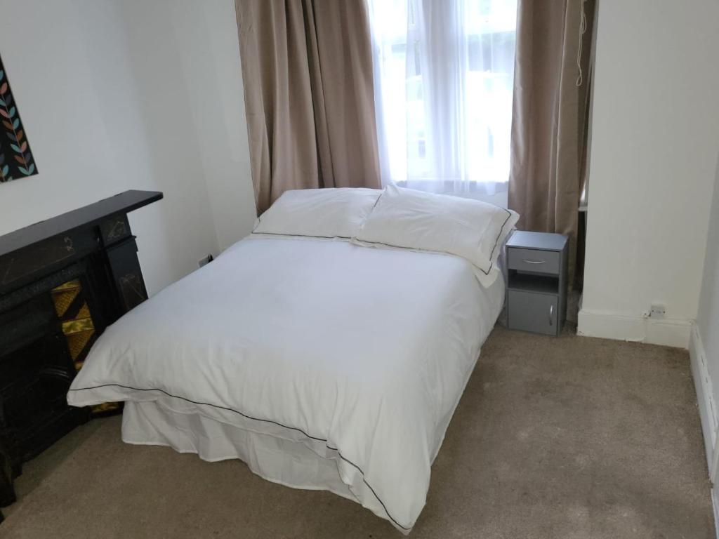 a bedroom with a bed with white sheets and a window at Affordable rooms in Gillingham in Gillingham