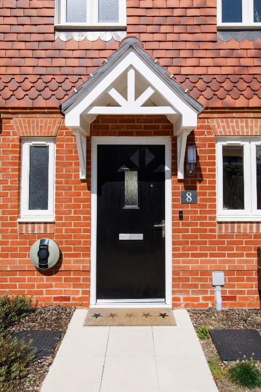 a black front door of a brick house at Sanderling House, walk to beach in Earnley