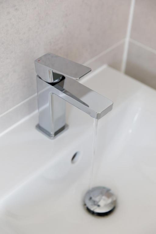 a silver sink in a bathroom with a drain at Sanderling House, walk to beach in Earnley