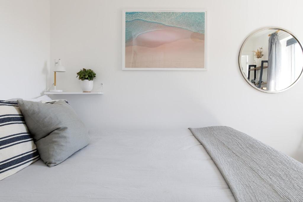 a white room with a bed and a mirror at Sanderling House, walk to beach in Earnley