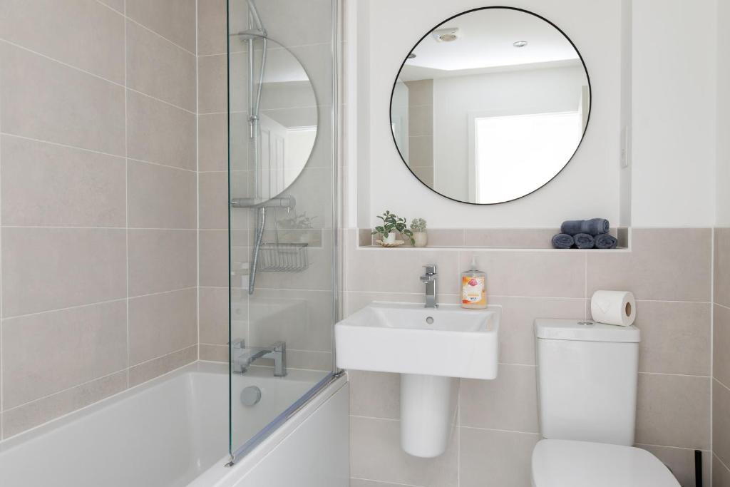 a white bathroom with a sink and a mirror at Sanderling House, walk to beach in Earnley