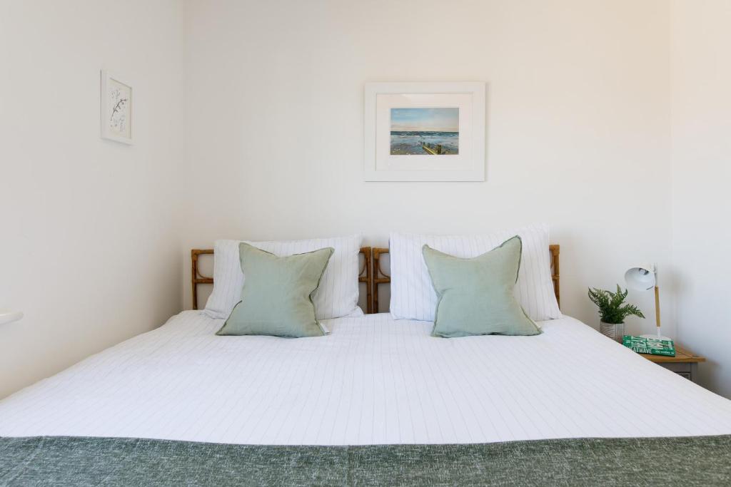 a bedroom with a white bed with two pillows at Sanderling House, walk to beach in Earnley