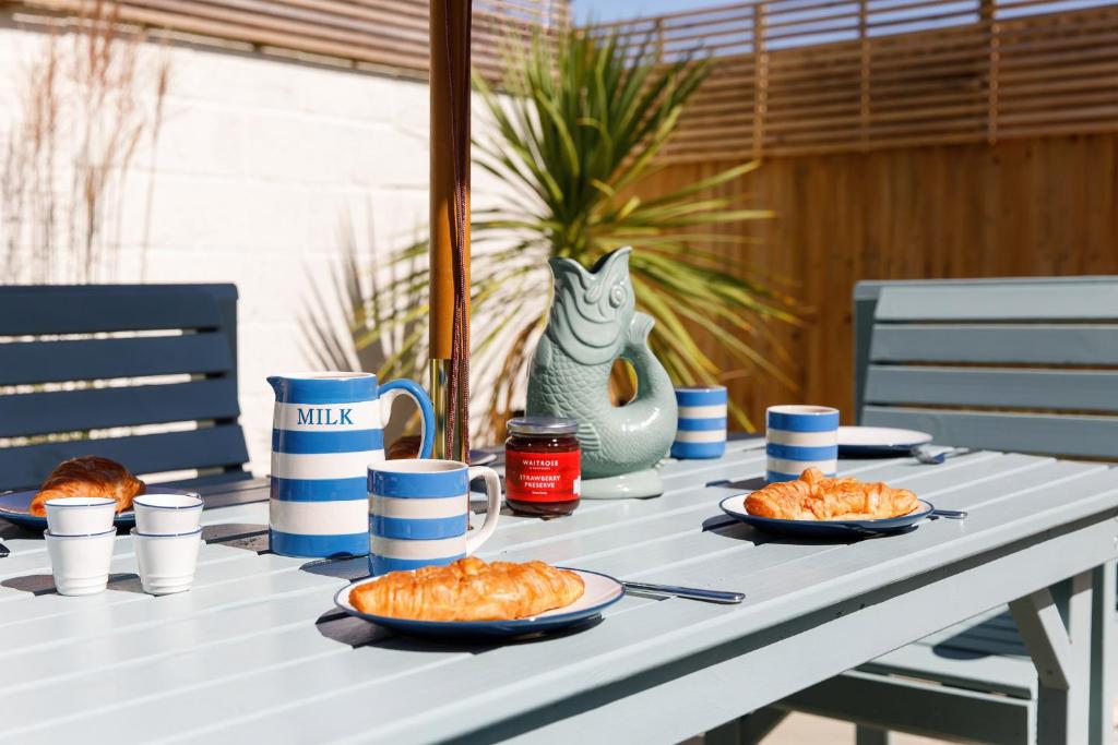 a white table with plates of food on it at Sanderling House, walk to beach in Earnley