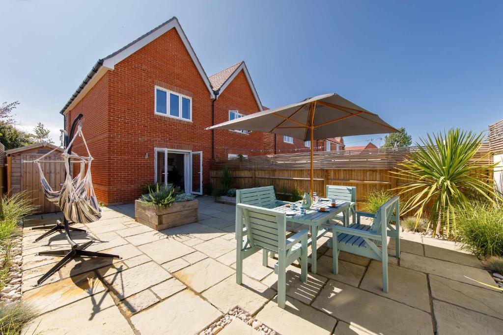 a patio with a table and an umbrella at Sanderling House, walk to beach in Earnley